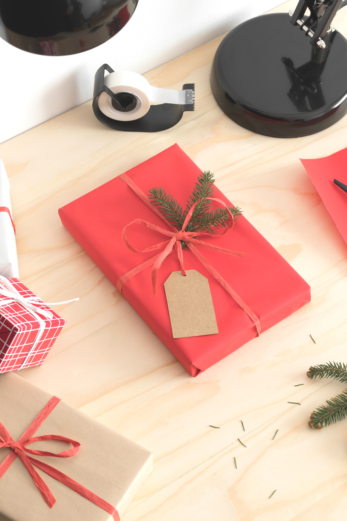Red christmas gift with workspace accessories on a wooden table.